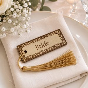 A handcrafted wooden table tag with a vibrant colored tassel designed by KatiStudioDesigns for event decor.